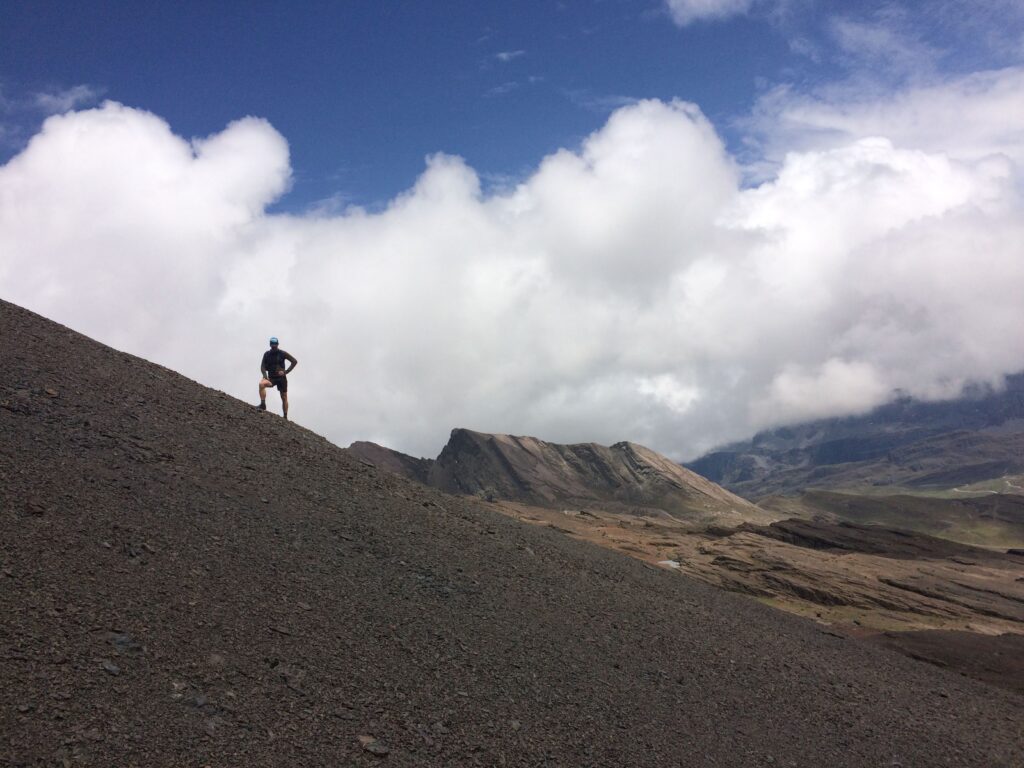Silhouetted figure standing on a rugged mountain slope under dramatic clouds, symbolizing personal challenge, reflection, and the journey of intentional fatherhood