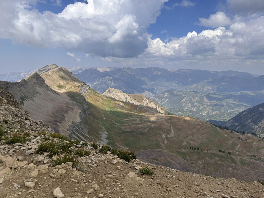 Expansive mountain landscape with rocky ridges and sunlit peaks under a dramatic sky, symbolizing perspective, challenge, and the journey toward intentional living