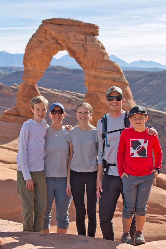 A family group stands together beneath Delicate Arch in Utah’s red rock wilderness — a moment of shared adventure, connection, and intentional presence. This image reflects PathForgeXP’s mission to guide fathers and families toward meaningful experiences that build lasting bonds and personal legacy.